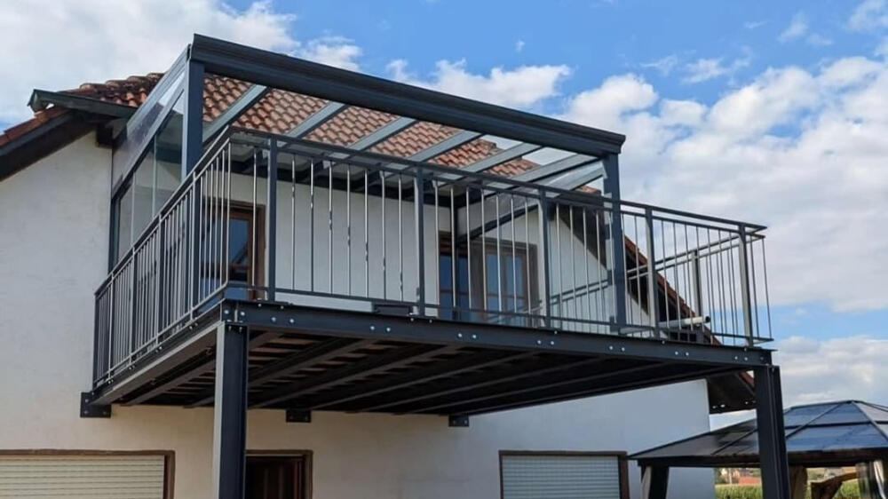 Maßgefertigte Balkonüberdachung mit schwarzer Aluminiumkonstruktion und Glasdach