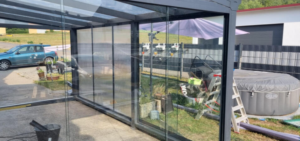 Rahmenlose Glasschiebeelemente als seitlicher Wetterschutz einer Terrassenüberdachung