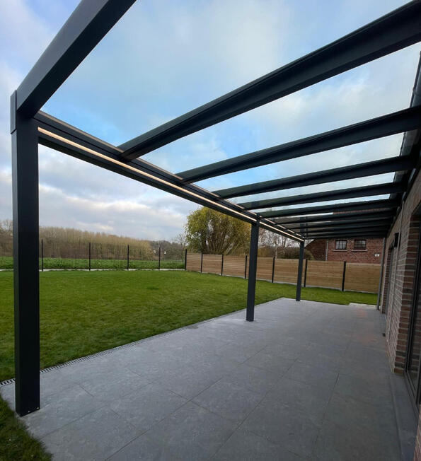 Großzügige Terrassenüberdachung mit dunkler Aluminiumkonstruktion und transparentem Dach